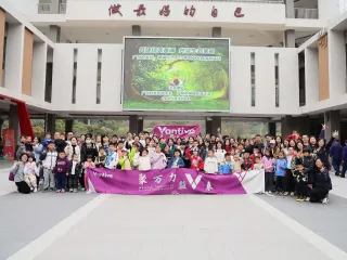 Large group of adults and children gathered outside a building, holding a Vantive banner