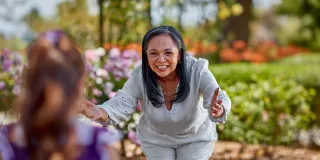 Woman holding out arms to give young girl a hug