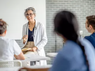 Female doctor in white coat discussing with coworkers in hospital setting